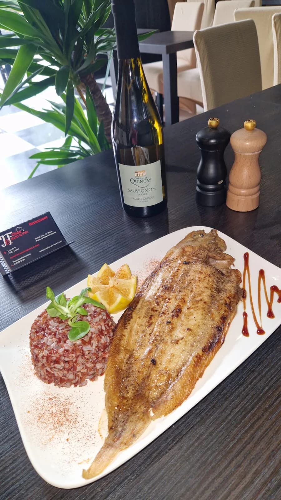 Poisson entier rôti présenté avec du riz rouge et des quartiers de citron